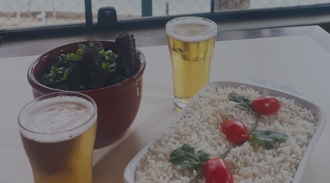 Dois copos de cerveja, travessa de arroz e cumbuca na mesa com o lago ao fundo