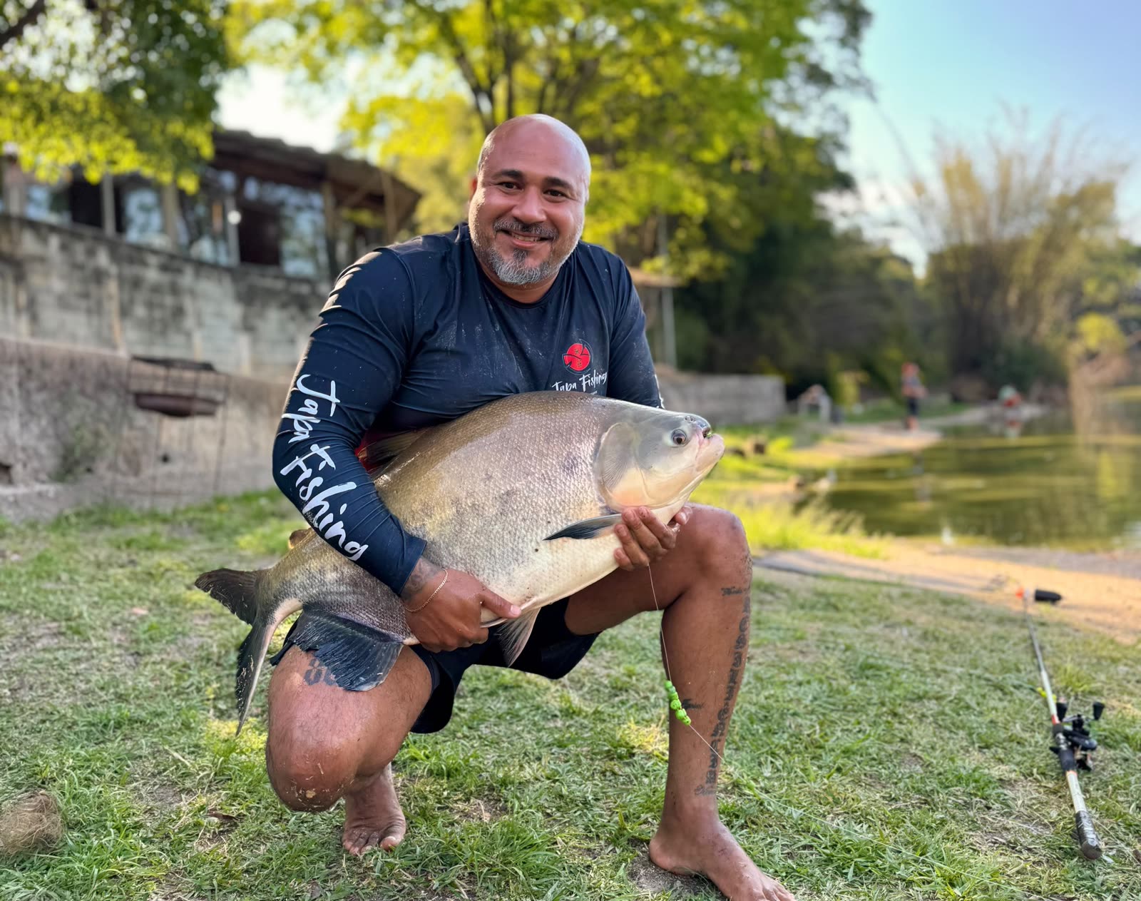 Rodrigo ajoelhado na grama segurando um tambacu